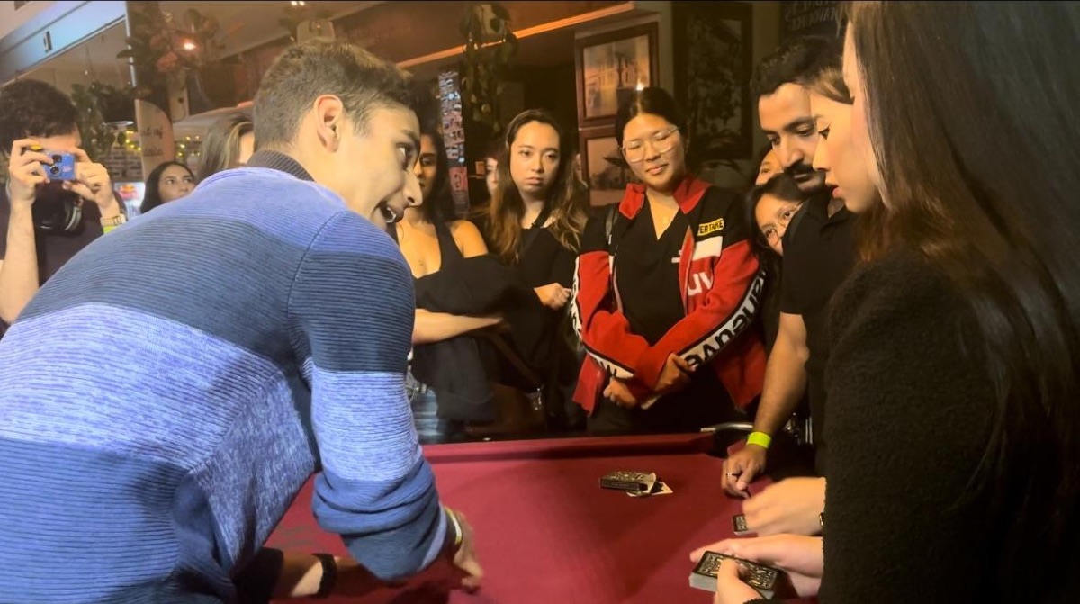 Mahir performing for a crowd gathered around a card table