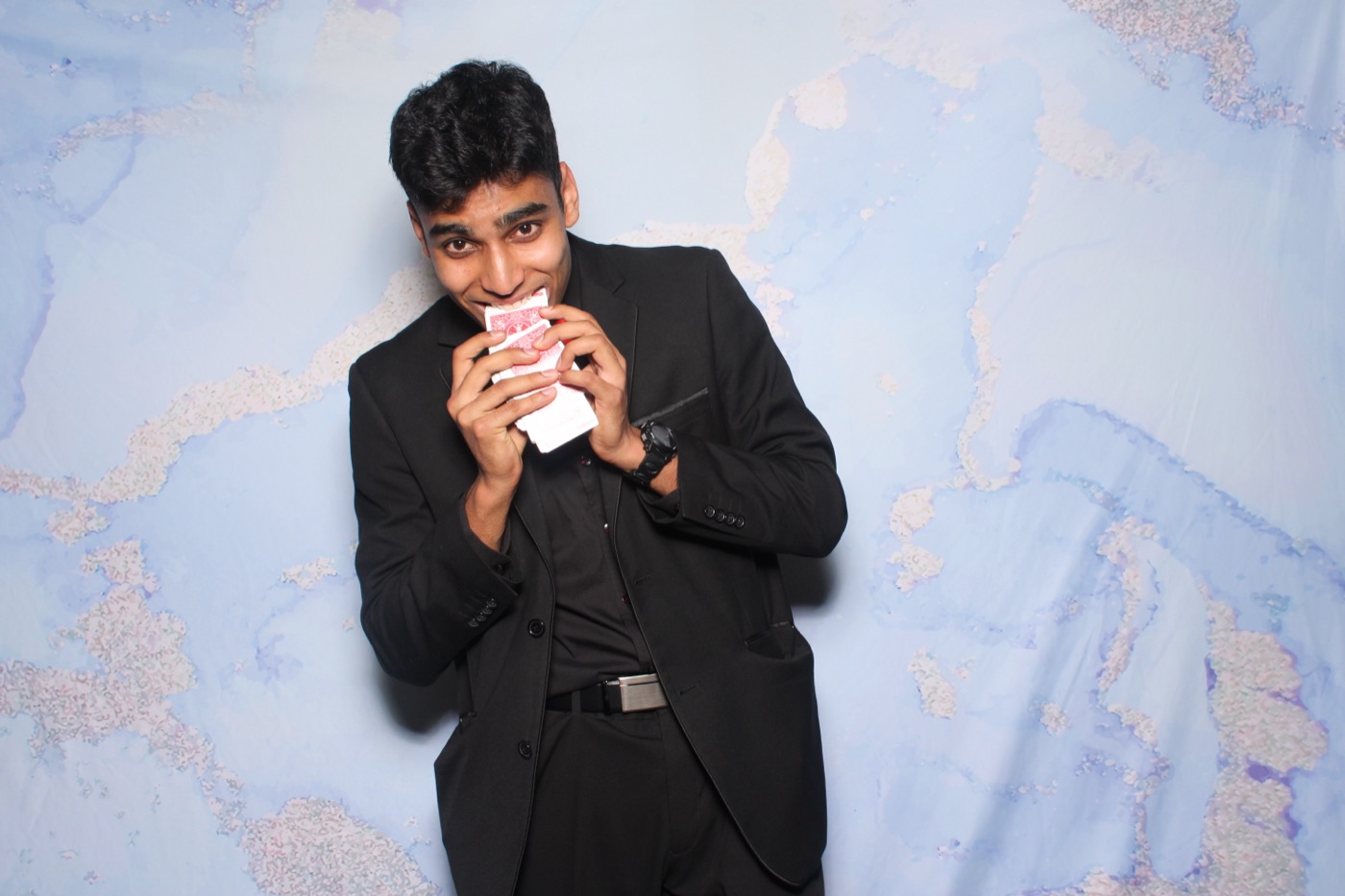 Mahir in a suit pretending to bite a deck of cards